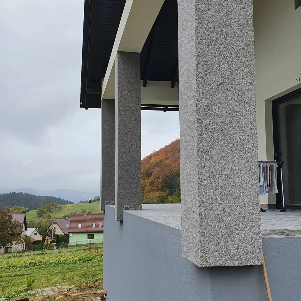 Detail modernej terasy s dekoratívnou omietkou na stĺpoch a výhľadom na jesennú krajinu