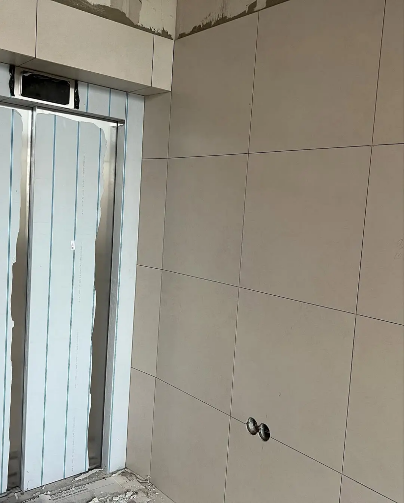 Detail realizácie obkladu steny pri výťahu veľkoformátovou béžovou dlažbou